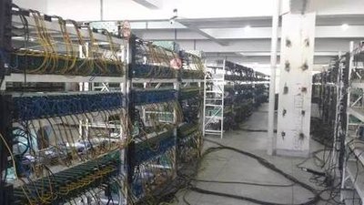A picture of a large mining farm showcasing numerous mining rigs housed in a warehouse setting.